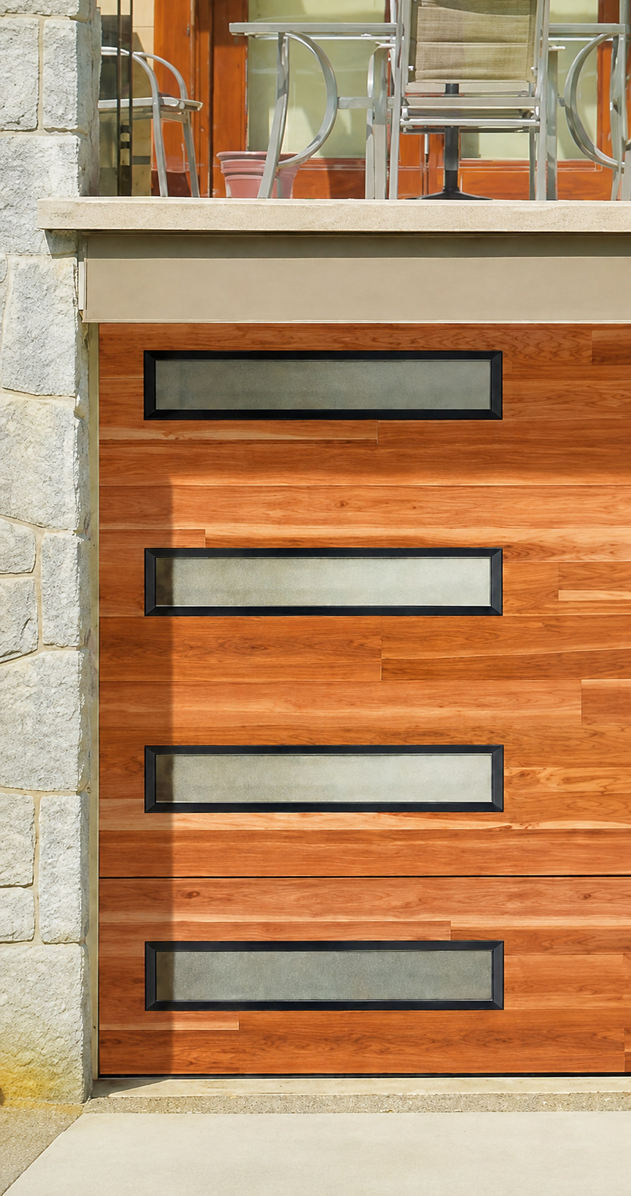 Cedar plank garage door with stacked windows on a stone home