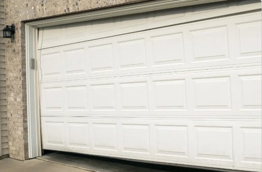 Garage door hanging off-track on a brick house