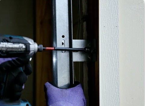 Technician drilling a bolt into a garage door track